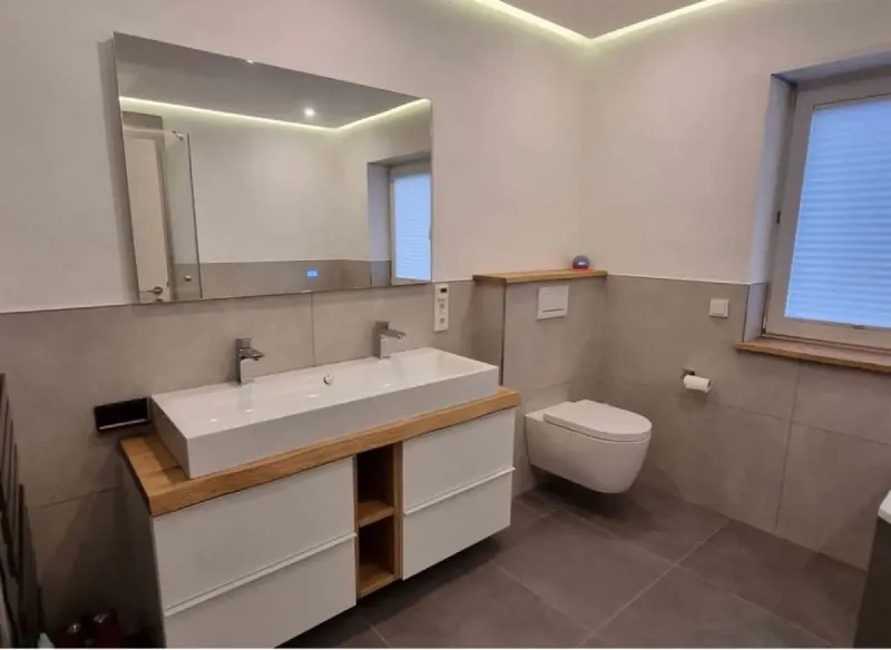 Modernes Bad mit grauen Fliesen und Holzelementen